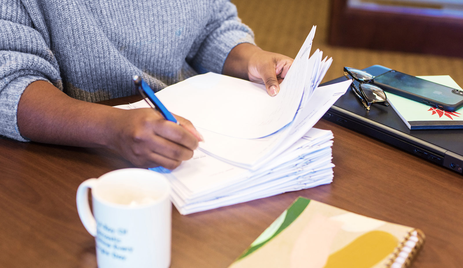 Woman writing on stack of paper