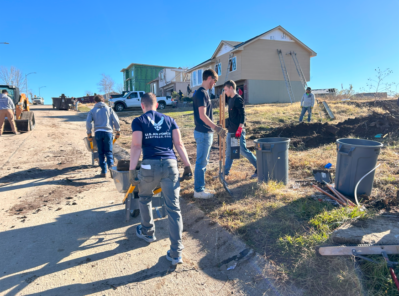 Volunteers ush wheelbarrows towards houses being re-sided